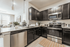 Modern kitchen with sleek dark cabinetry, stainless steel appliances, and a cozy open-concept living area.