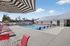 Inviting outdoor pool area with colorful sun loungers, stylish umbrellas, and a modern clubhouse backdrop under a clear blue sky.