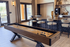 Contemporary recreational lounge featuring a sleek shuffleboard table, stylish bar stools, and chic decor accents.