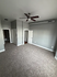 Spacious, modern room with plush carpeting, sleek gray walls, and a stylish ceiling fan, perfect for a cozy bedroom or chic office space.