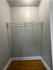 Spacious walk-in closet with sleek white walls, a durable wire shelf, and warm wooden flooring, perfect for ample storage and organization.