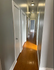 Bright hallway with sleek hardwood flooring and modern lighting, leading to a cozy, inviting room.