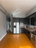 Modern kitchen with sleek dark cabinetry, stainless steel appliances, and elegant hardwood floors offering a contemporary cooking experience.
