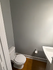 Modern half bathroom with sleek fixtures, fresh gray walls, and warm wooden flooring adding a touch of elegance.
