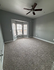 Inviting bedroom with plush carpet, large bay window, and stylish ceiling fan, perfect for creating your cozy retreat.