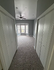 Inviting hallway leading to a sunlit room with cozy carpet flooring and large bay window, perfect for relaxation.
