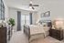 Elegant bedroom with chic decor, featuring a comfortable bed with plush pillows, stylish wooden furniture, and ample natural light from large window.