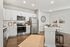 Chic and modern kitchen featuring sleek stainless steel appliances, bright white cabinetry, and an elegant island with bar seating. Perfect for culinary enthusiasts and entertaining guests.