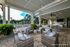 Luxurious outdoor lounge area with wicker seating and lush greenery overlooking a sparkling pool, perfect for relaxation and entertainment.