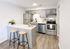 Modern kitchen with sleek gray cabinets, stainless steel appliances, and a cozy breakfast bar featuring stylish wooden stools.