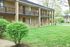 Charming apartment building with brick facade, lush green landscaping, and inviting balconies perfect for relaxation.