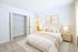Bright and inviting bedroom with a cozy bed, elegant furnishings, soft neutral tones, and ample natural light.