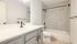 Modern bathroom with elegant gray tiles, a sleek vanity, and contemporary fixtures, offering a serene and luxurious atmosphere.
