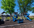 Inviting playground with blue slides and climbing structures set against lush green trees, perfect for family enjoyment.
