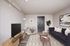 Modern living room with stylish decor, featuring a sleek navy sofa, cozy armchair, and chic wooden coffee table, enhanced by elegant artwork and vibrant greenery.
