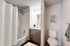 Elegant bathroom featuring a sleek marble countertop, modern fixtures, and a relaxing bathtub with a stylish curtain.