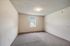 Bright and spacious bedroom with plush carpet and natural light from a large window, perfect for a cozy retreat.