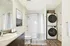 Bright bathroom with a bathtub, modern vanity, and in-unit stacked washer and dryer.