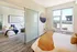 Cozy apartment interior featuring a bright bedroom with a knitted throw, large window, and adjoining stylish living room.