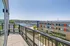 Balcony overlooking a vibrant waterfront and modern building, with a sunny, scenic view.