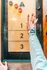 Hand engaging with shuffleboard game on a wooden table with numbered sections.