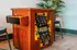 Vintage arcade game console with vibrant graphics and a wooden finish, flanked by modern bar stools and a lush plant.