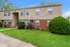Charming duplex with classic brick and siding exterior, surrounded by lush greenery and a well-maintained lawn.