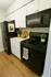 Chic modern kitchen with sleek black appliances, white cabinetry, and a warm wood floor. Fresh herbs and lemons add a vibrant touch.