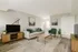 Cozy and modern living room with a stylish sofa, green accents, and elegant wooden furniture, perfect for relaxation.