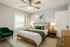 Inviting bedroom with a modern aesthetic, featuring a wooden bed, cozy green accents, and elegant decor, perfect for relaxation.