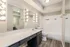 Elegant bathroom featuring a sleek vanity with bright Hollywood-style lighting, spacious countertop, and a modern bathtub with white tile backsplash.