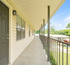 Inviting outdoor hallway with modern railing and bright siding, leading to apartments with scenic views.