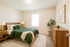 Bright and inviting bedroom featuring a plush green bedspread, elegant wooden furniture, and tasteful decor, perfect for a cozy retreat.
