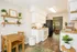 Charming kitchen in a cozy apartment featuring modern appliances, open shelving with plants, and a quaint dining area.
