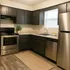 Modern kitchen with sleek dark cabinets, stainless steel appliances, and natural light.