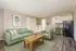 Inviting living space with elegant green sofas, wooden coffee table, and an open kitchen with modern appliances and bar stools.