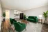 Modern living room with stylish green furniture and a cozy, open-plan layout leading to a functional kitchen.