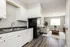 Charming open-concept kitchen and living area featuring sleek hardwood floors, modern white cabinetry, and bright natural light.