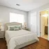 Inviting bedroom with natural light, elegant wooden flooring, cozy queen-sized bed, and a modern en-suite bathroom.