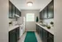 Contemporary galley kitchen with sleek dark cabinets, modern appliances, and vibrant accents, offering a stylish and functional space.