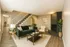 Charming living room with plush green sofa, cozy fireplace, and elegant staircase, perfect for modern comfort.