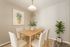 Elegant dining area featuring a wooden table, six upholstered chairs, and vibrant greenery accents for a modern touch.