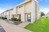 Charming apartment building with modern siding, lush greenery, and a welcoming private entrance.