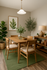 Elegant dining area with a wooden table set, cozy lighting, and lush greenery creating a serene atmosphere.