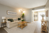 Inviting living room with farmhouse decor, cozy beige sofa, and stylish wooden accents, leading into a bright, contemporary kitchen.