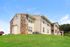 Charming apartment building with modern stone accents, nestled on lush green lawns under a clear blue sky.