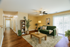 Inviting living room with a plush green sofa, contemporary decor, and natural light streaming through large glass doors, with elegant wood flooring.