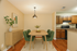 Inviting dining area with elegant wooden table, stylish green chairs, and modern kitchen access, creating a warm and welcoming atmosphere.