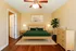 Inviting bedroom with elegant design, featuring a cozy green bed, stylish wooden furniture, and warm lighting.