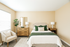 Inviting bedroom with modern decor, featuring a cozy bed with plush green accents, elegant wooden furniture, and a sunlit ambiance.